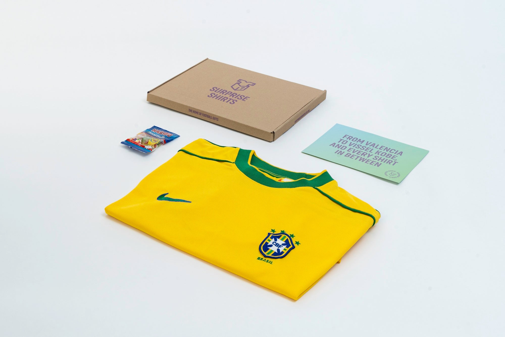 A 1998 Brazil home shirt laid next to a bag of Haribo, a Surprise Shirts box and an info card.