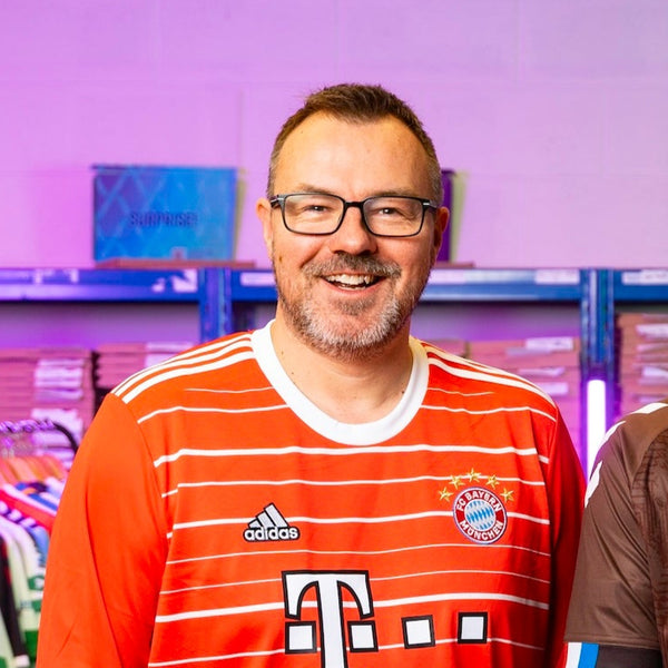 Rob smiles at the camera, wearing a red Bayern Munich 22/23 home shirt.